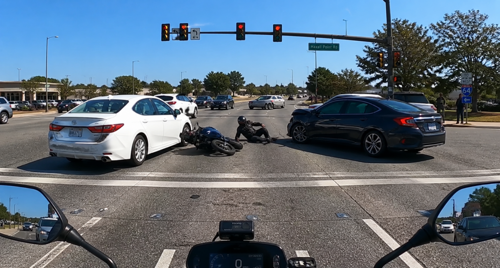 Motorcycle dash cam capturing accident scene with vehicles and traffic signals visible